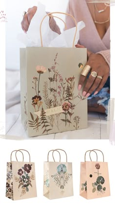 a woman is holding three bags with flowers on them and the bag has gold handles