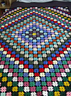 a crocheted blanket on a bed with pillows and blankets in the shape of flowers