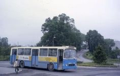 a blue and yellow bus parked on the side of a road next to a person riding a bike