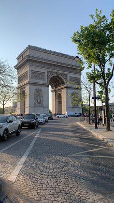 cars are parked in front of the arc de trioe on a sunny day,