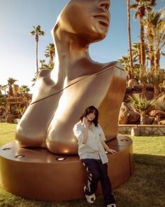 a woman is standing in front of a large statue with her hands on her hips