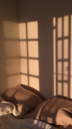 the sunlight is shining through two windows onto a bed with pillows and blankets on it