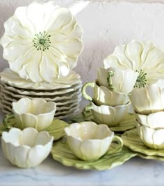 a table topped with lots of white flowers next to plates and cups on top of a counter