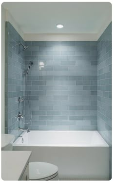 a white toilet sitting next to a bath tub in a bathroom under a light fixture