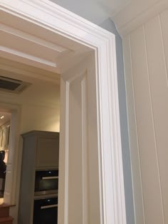 an open door leading into a kitchen with white walls and trimming on the wall