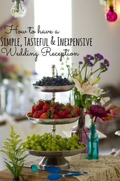 a table topped with three tiered trays filled with fruits and vegetables next to wine glasses