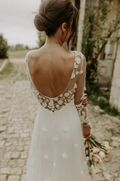 the back of a woman's wedding dress, with flowers on her shoulder and long sleeves