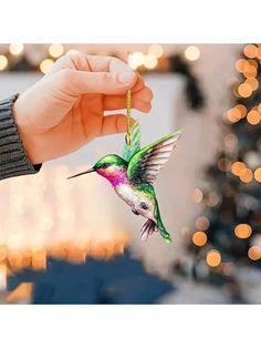 a person holding a hummingbird ornament in their hand