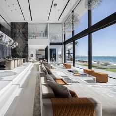 a large living room with high ceilings and floor to ceiling windows looking out onto the ocean