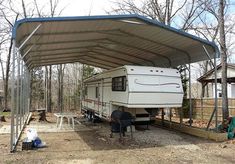 an rv is parked under a carport in the woods