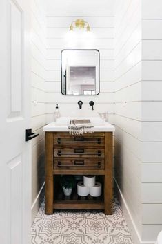 a bathroom with a sink, mirror and two buckets