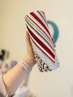 a woman holding up a red, white and blue striped purse with sequins