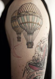 a man with a tattoo on his arm has a hot air balloon in the sky