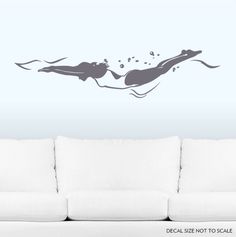 a white couch sitting in front of a wall with a drawing of two people swimming