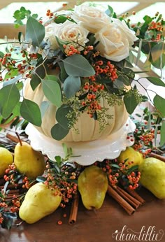 there is a cake with flowers and fruit on the top, surrounded by greenery