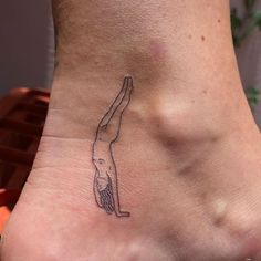 a woman's foot with a small tattoo on the side of her leg that has a person doing a handstand