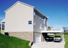 a car is parked in front of a two story house on the side of a hill