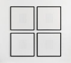 four black and white square paintings hanging on a wall next to a vase with flowers in it