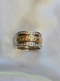 two wedding bands with diamonds on them sitting on a white cloth covered tablecloth in close up view