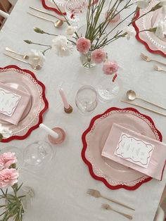 the table is set with pink and white plates, silverware, and napkins