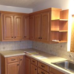 an empty kitchen with wooden cabinets and white counter tops, is pictured in this image