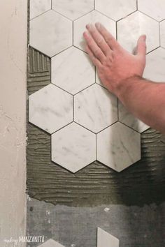 a man is holding his hand on the tile in front of hexagonal tiles