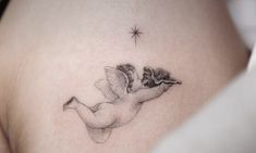 a woman's stomach with a small tattoo on the side of her breast and an angel flying above it