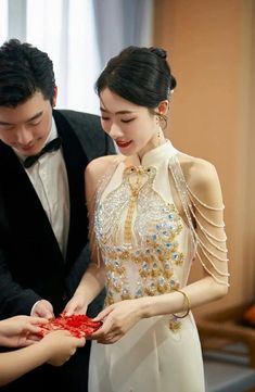 two people standing next to each other in front of a red piece of cloth on top of a table