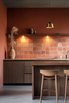 two wooden stools sit in front of a kitchen island with copper lights on it