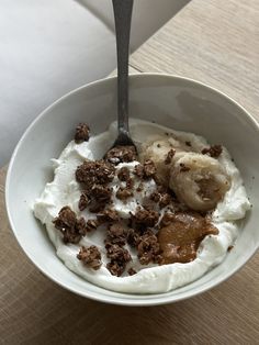 a bowl filled with yogurt and granola on top of a wooden table