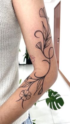 a woman's arm with flowers and leaves tattooed on the left side of her arm