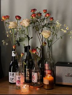 several bottles with flowers in them on a table next to candles and a radio player