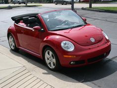 a red convertible car is parked on the street