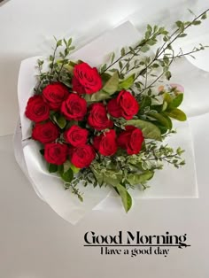 a bouquet of red roses sitting on top of a white paper with the words, good morning i have a good day