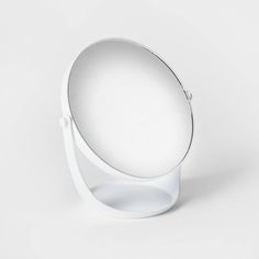 a white circular mirror on top of a stand with an object in the middle that looks like it is floating