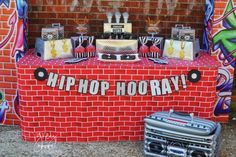 a red table topped with lots of cake next to a brick wall