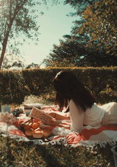 a woman laying on top of a blanket in the grass