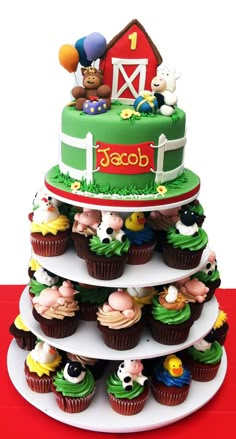 a three tiered cake with cupcakes and farm animals on it