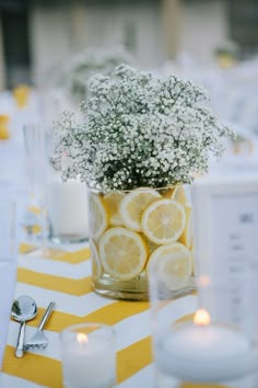 a vase filled with lemons and baby's breath on top of a table