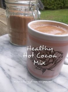 a close up of a cup of coffee on a table with a mason jar in the background