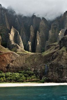 the mountains are covered in clouds and water as it sits on top of an island