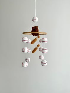 a baseball themed mobile hangs from a wooden stick with balls hanging from it's end