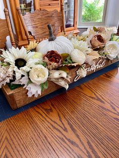 a wooden table topped with white flowers and pumpkins