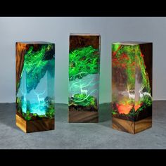 three wooden boxes with paintings on them in the shape of trees and water, one is green