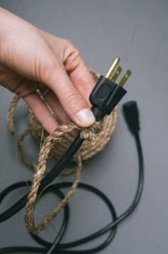 a person is holding an electronic device in their hand and plugged into the cord