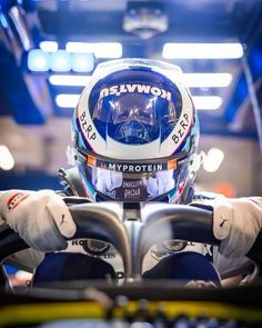 a person in a racing car wearing a helmet and driving gloves with both hands on the steering wheel