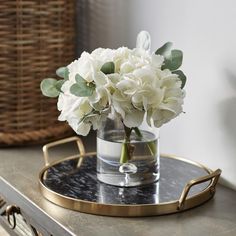 white flowers in a glass vase on a tray