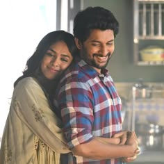 a man holding a woman in his arms and looking at the camera while she smiles