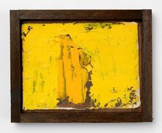 an abstract painting with yellow and brown colors in a wooden frame on a white wall