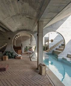 an indoor swimming pool in the middle of a concrete building with circular mirrors above it